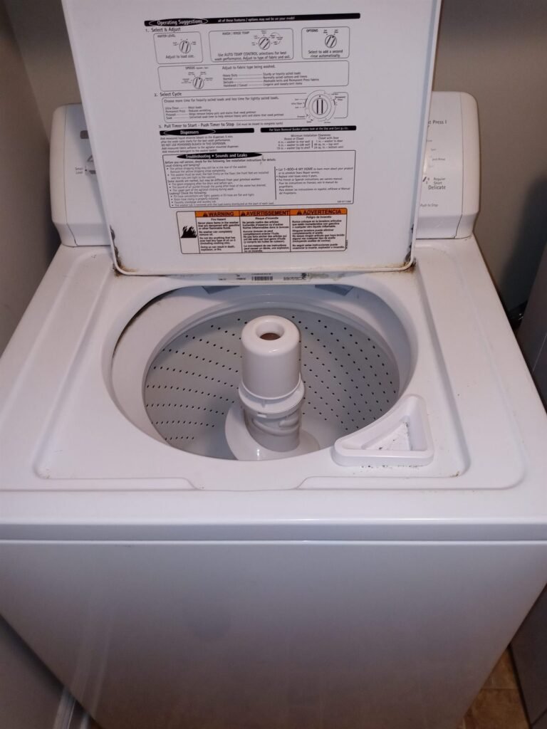 Top-load washing machine opened up for repair, showing the agitator and wash basket
