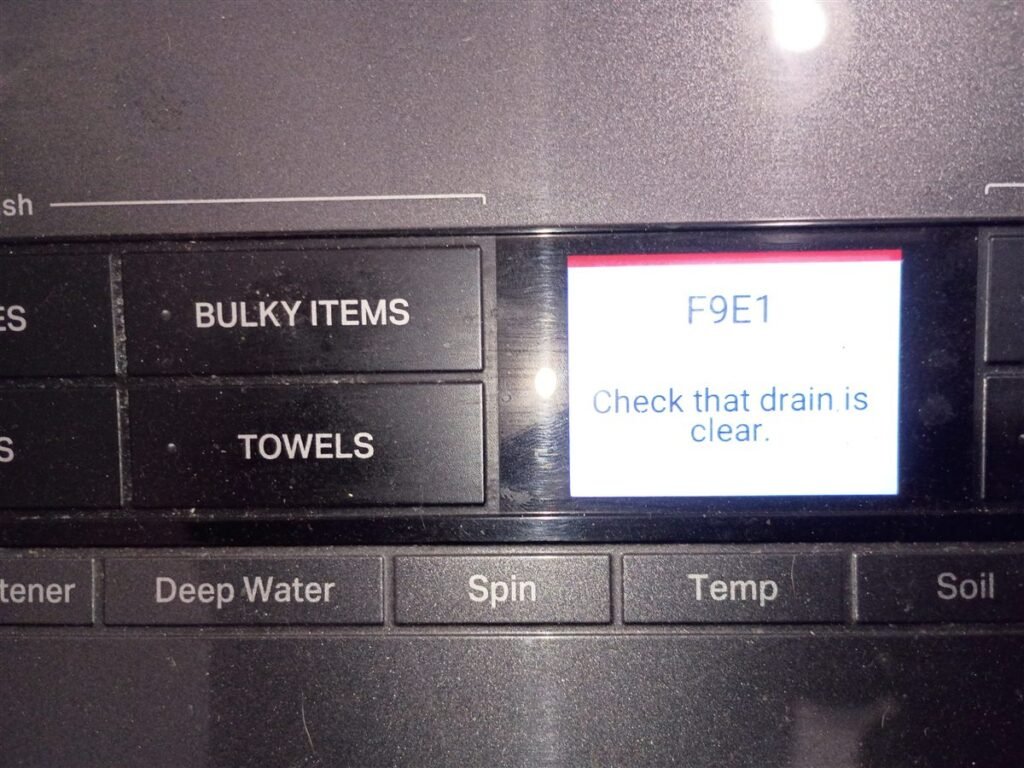 Washing machine display showing error code F9E1 with the message Check that drain is clear